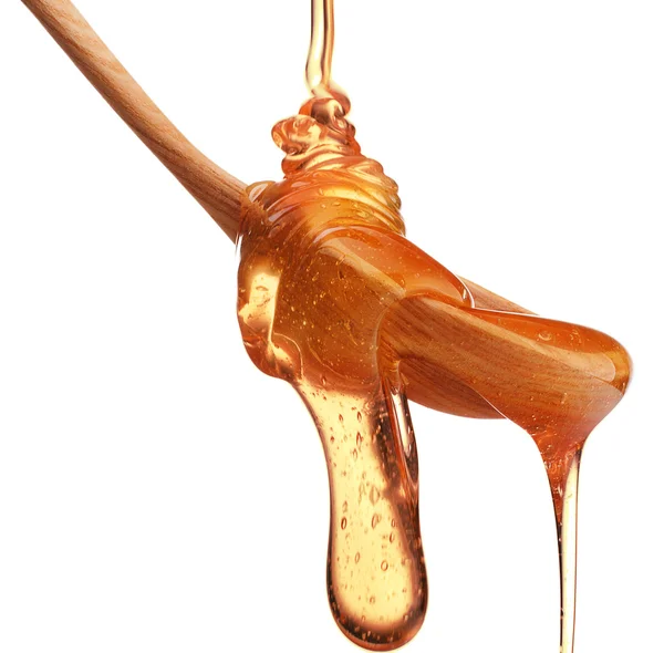 Honey dripping from wooden spoon — Stock Photo, Image