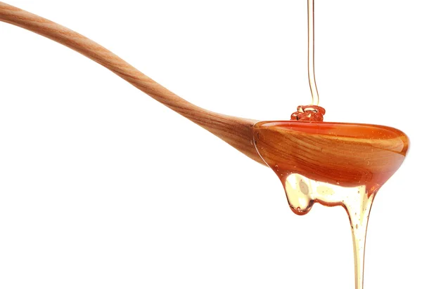 Honey dripping from wooden dipper — Stock Photo, Image