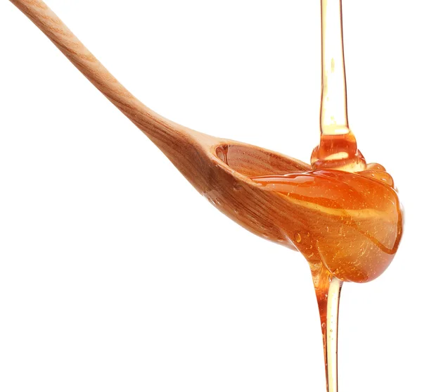 Honey dripping on wooden spoon — Stock Photo, Image