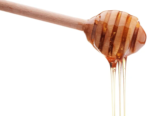 Honey dripping from wooden honey dipper — Stock Photo, Image