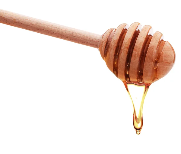 Honey dripping from wooden honey dipper — Stock Photo, Image