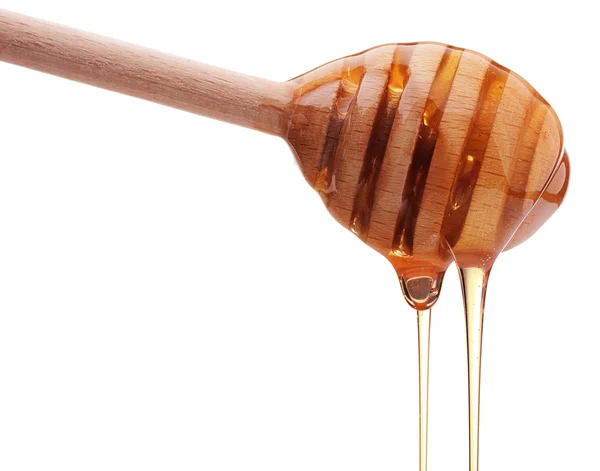 Honey dripping from wooden honey dipper — Stock Photo, Image