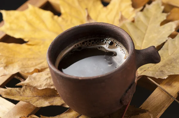 Šálek kávy a podzimní listí na dřevěný stůl. — Stock fotografie