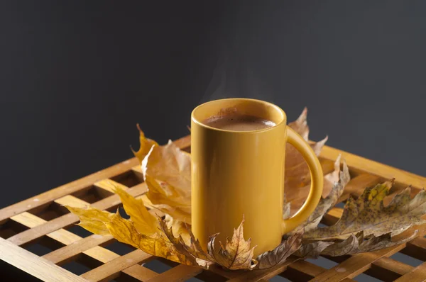 Tazza di caffè e foglie autunnali su un tavolo di legno . — Foto Stock