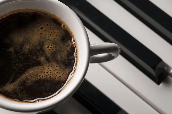 Coffee cup on piano keyboard — Stock Photo, Image