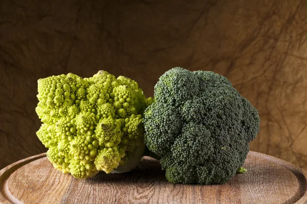 Broccoli and romanesco cauliflower on a wooden cutting board — Stock Photo, Image