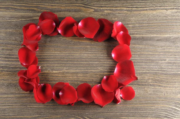 Frame of red rose petals on a wood background. — Stock Photo, Image