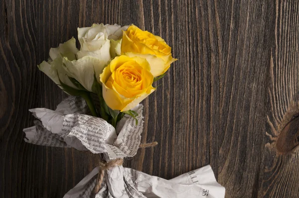 Bukiet kwiatów róży multicolor zawinięte w gazetę nad drewnianym tarasem — Zdjęcie stockowe