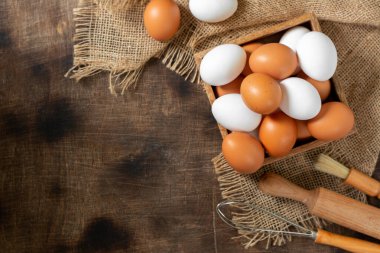 Mutfak masasındaki tepside yumurtalar. Beyaz ve kahverengi yumurtalar çırpılmış ve oklavalı. Mutfak arka planında tavuk yumurtası ve çırpma. Pişirme hazırlığı kavramı. Kopyalama alanı olan üst görünüm