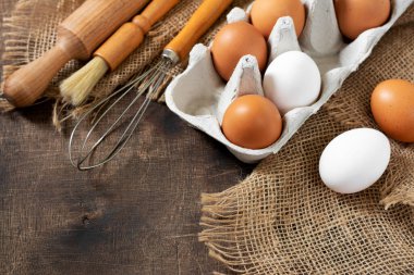 Mutfak masasındaki tepside yumurtalar. Beyaz ve kahverengi yumurtalar çırpılmış ve oklavalı. Mutfak arka planında tavuk yumurtası ve çırpma. Pişirme hazırlığı kavramı. Kopyalama alanı