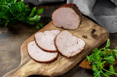 Kahverengi ahşap bir masada, tahta bir tahtanın üzerinde otlu rulo köfte. Pişmiş et. Kırsal biçim