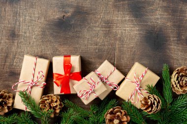 El işi kağıdında hediye kutuları. Noel arkaplanı. Kahverengi ahşap arka planda ladin dalları altında Noel hediyeleri. Düz Noel. Kopyalama uzayından en üst görünüm