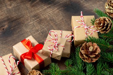 El işi kağıdında hediye kutuları. Noel arkaplanı. Kahverengi ahşap arka planda ladin dalları altında Noel hediyeleri. Düz Noel. Kopyalama uzayından en üst görünüm