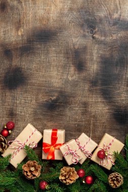 El işi kağıdında hediye kutuları. Noel arkaplanı. Kahverengi ahşap arka planda ladin dalları altında Noel hediyeleri. Düz Noel. Kopyalama uzayından en üst görünüm
