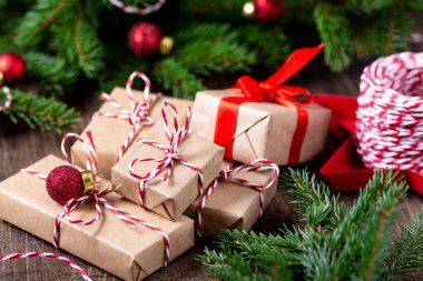 El işi kağıdında hediye kutuları. Noel arkaplanı. Kahverengi ahşap arka planda ladin dalları altında Noel hediyeleri