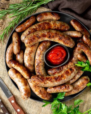 Kızarmış sosis. Baharatlı ve sosisli Bavyera ve Nuremberg sosisleri. Kahverengi ahşap bir masada siyah seramik tabakta lezzetli et sosisleri. Alman yemeği.