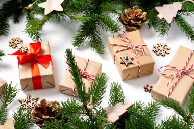 El işi kağıdında hediye kutuları. Noel arkaplanı. Beyaz arka planda ahşap süslemelerle süslenmiş ladin dalları altında Noel hediyeleri