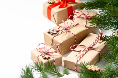 El işi kağıdında hediye kutuları. Noel arkaplanı. Beyaz arka planda ahşap süslemelerle süslenmiş ladin dalları altında Noel hediyeleri