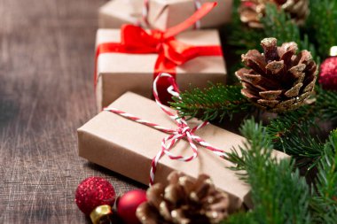 El işi kağıdında hediye kutuları. Noel arkaplanı. Kahverengi ahşap arka planda ladin dalları altında Noel hediyeleri. Düz Noel. opyspace