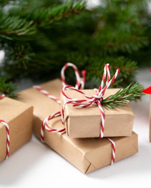 El işi kağıdında hediye kutuları. Noel arkaplanı. Beyaz arka planda ahşap süslemelerle süslenmiş ladin dalları altında Noel hediyeleri