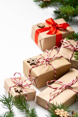 El işi kağıdında hediye kutuları. Noel arkaplanı. Beyaz arka planda ahşap süslemelerle süslenmiş ladin dalları altında Noel hediyeleri. Kopyalama alanı