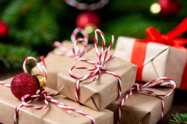 El işi kağıdında hediye kutuları. Noel arkaplanı. Kahverengi ahşap arka planda ladin dalları altında Noel hediyeleri