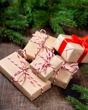 El işi kağıdında hediye kutuları. Noel arkaplanı. Kahverengi ahşap arka planda ladin dalları altında Noel hediyeleri