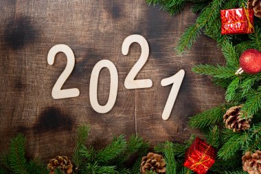 Mutlu yıllar 2021. 2021 numara kahverengi ahşap zemin üzerinde ahşaptan yapılmıştır. Noel arkaplanı, köknar dallarıyla süslenmiş. Düzgünce
