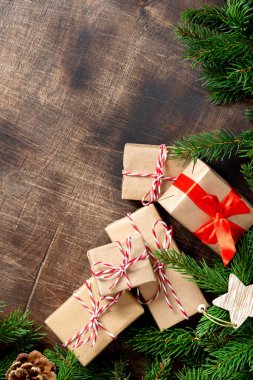El işi kağıdında hediye kutuları. Noel arkaplanı. Kahverengi ahşap arka planda ladin dalları altında Noel hediyeleri. Düz Noel. Kopyalama uzayından en üst görünüm