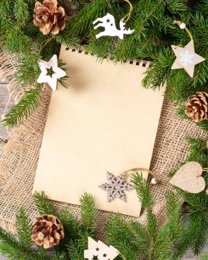 Noel ya da yeni yıl arkaplanı boş bir not defteri, ladin dalları ve Noel çevre dostu ahşap süslemelerle dolu. Kontrol listesi ya da Noel Baba 'ya mektup. Noel tebrik kartı. Kopyalama alanı