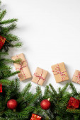 Dárkové krabice v řemeslném papíru. Vánoční pozadí. Vánoční dárky pod smrkovými větvemi zdobené dřevěnými ozdobami na bílém pozadí. Copyspace