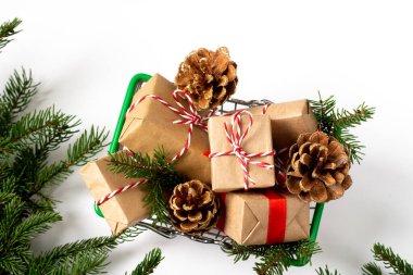 Beyaz arka planda alışveriş arabasında bir sürü Noel ve yeni yıl hediyesi var. Noel hediyesi alma fikri. Noel alışverişi