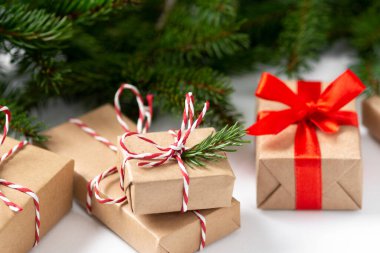 El işi kağıdında hediye kutuları. Noel arkaplanı. Beyaz arka planda ahşap süslemelerle süslenmiş ladin dalları altında Noel hediyeleri