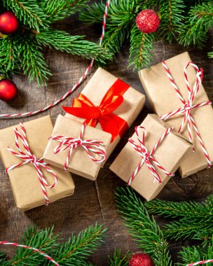 El işi kağıdında hediye kutuları. Noel arkaplanı. Kahverengi ahşap arka planda ladin dalları altında Noel hediyeleri. Düz Noel. Üst görünüm