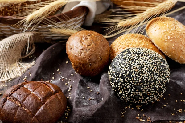Wheat and rye bread. Rye and wheat bread of different shapes on a brown wooden table. Baguettes, loaves, round bread, buns and Burger buns on the table