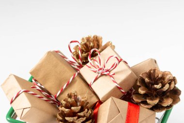 Beyaz arka planda alışveriş arabasında bir sürü Noel ve yeni yıl hediyesi var. Noel hediyesi alma fikri. Noel alışverişi