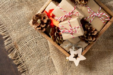 Çevre dostu el sanatları kağıdında noel hediyesi kutuları. Tahta bir masanın üzerindeki tahta kutuda hediyeler. Çevre dostu hediye paketi