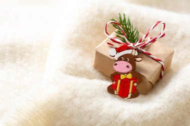 El işi kağıdında hediye. 2021 boğa ineğinin ahşap sembolüyle süslenmiş yeni yıl hediyesi. Noel ya da yeni yıl hediyesi. Yakın plan.