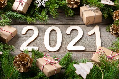 Mutlu yıllar 2021. 2021 numara kahverengi ahşap zemin üzerinde ahşaptan yapılmıştır. Köknar dallı Noel arkaplanı