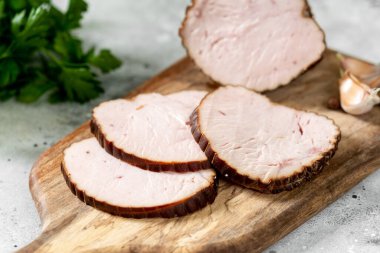 Açık gri bir masada, ahşap servis tahtasında otlu köfte. Pişmiş et