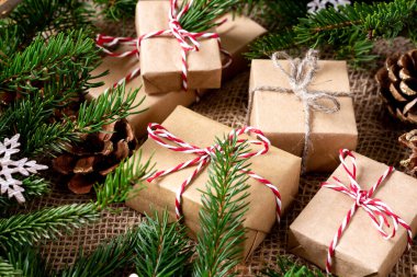 El işi kağıdında hediye kutuları. Noel arkaplanı. Kahverengi ahşap arka planda ladin dalları altında Noel hediyeleri