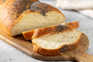 Ahşap zemin üzerinde haşhaş tohumu olan ev yapımı kabuklu buğday şekerli çörek. Durgun hayat, karanlık ruh hali, afiş düzeni. Geleneksel teknikler fırın kavramı