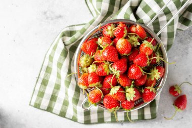 Çilekli. Açık gri arka planda metal bir kasede çilek. Bir sürü çilek. Kopyalama alanı olan üst görünüm