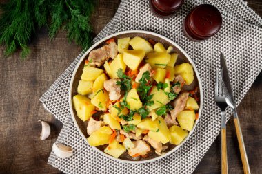 Etli haşlanmış patates. Kahverengi bir masada seramik tabakta domuz etiyle kızarmış patates.