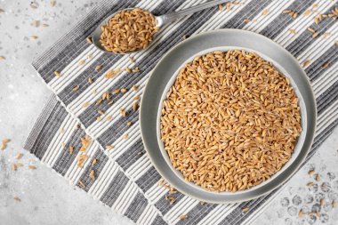 Açık gri mutfak masasında seramik bir kasede kepekli buğday. Sağlıklı beslenme için hecelenen mısır gevreği kültürü