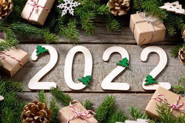 Mutlu yıllar 2022. 2022 numara ahşap zemin üzerinde ahşaptan yapılmıştır. Noel arkaplanı köknar dallarıyla dolu. ECO dekorasyonları