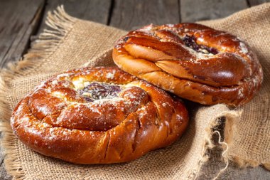 Ahşap bir masada reçelli çörekler. Kiraz reçelli turta ve badem ezmesi. Kaba lezzetli hamur işleri.