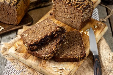 Servis tahtasında ayçekirdeği olan çavdar ekmeği. Tahtadaki tahta kırsal bir masada duran ekmek parçaları. Sağlıklı çavdar ekmeği