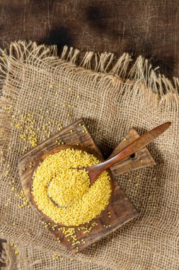 Millet. Millet ahşap bir kaşıkta kase ve ahşap bir mutfak masasında.