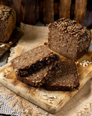  Servis tahtasında ayçekirdeği olan çavdar ekmeği. Tahtadaki tahta kırsal bir masada duran ekmek parçaları. Sağlıklı çavdar ekmeği